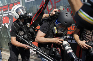 A Turkish riot policeman pushes a photographer during a protest at Taksim Square in Istanbul